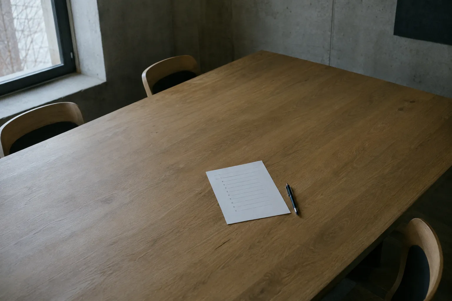 A single sheet with a short list alone in the middle of a large empty meeting table.