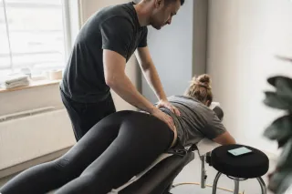 A physiotherapist treating a patient on a bench while the phone lights up unanswered beside them